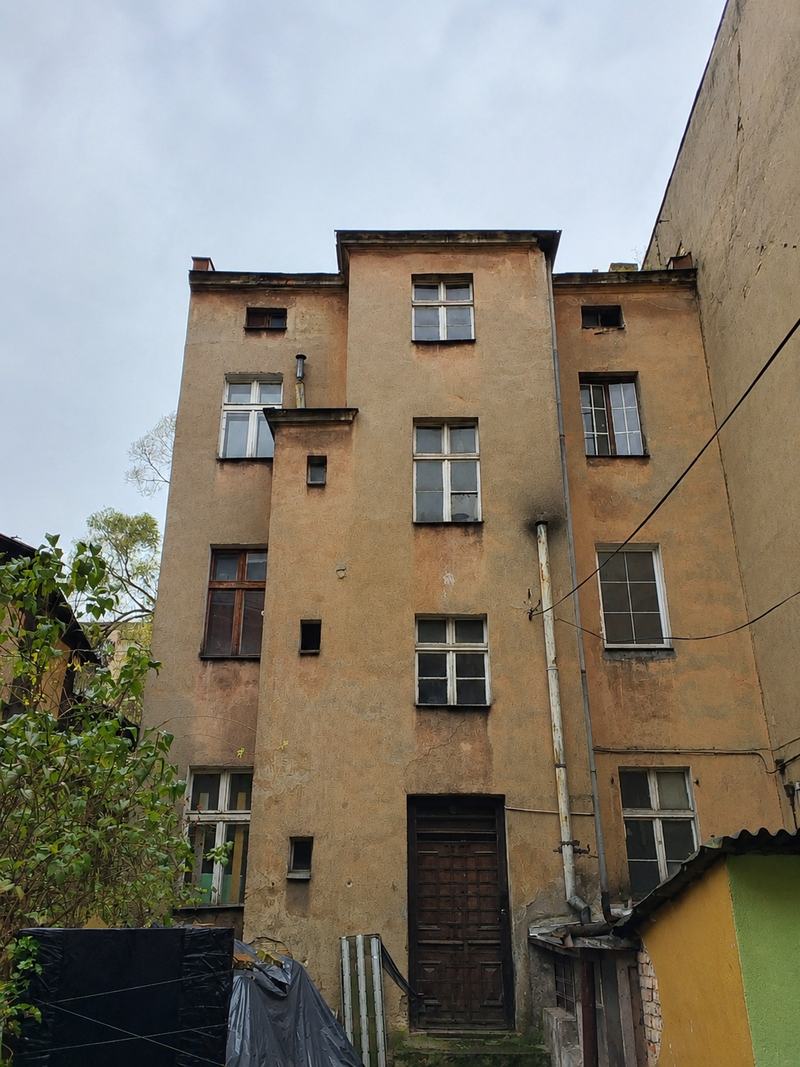 Kamienica przed rewitalizacją — elewacja od podwórza, spękany tynk i stara stolarka